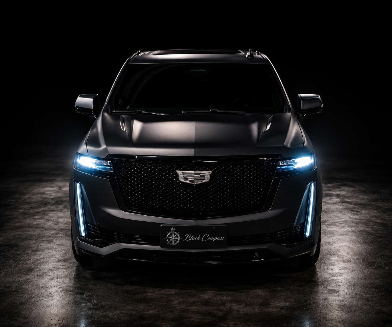 Black Compass signature showroom with a black Cadillac Escalade under dramatic lighting